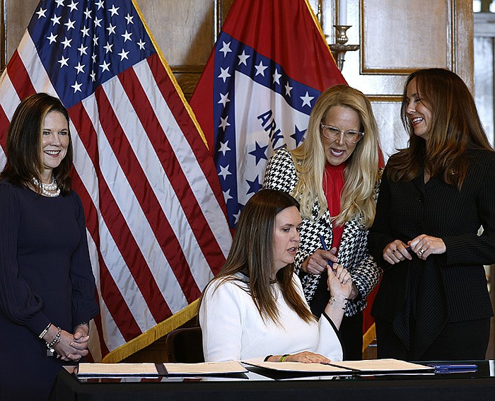 Gov. Sarah Huckabee Sanders hands a pen to Rep. DeAnn Vaught, R-Horatio, as Kristi Putnam (left), Secretary of the Arkansas Department of Human Services, and Sen. Missy Irvin (right), R-Mountain View, look on during a ceremonial bill signing for a law allowing up to 12 weeks of maternity leave for state employees on Monday, April 24, 2023 at the state Capitol in Little Rock. 
(Arkansas Democrat-Gazette/Thomas Metthe)