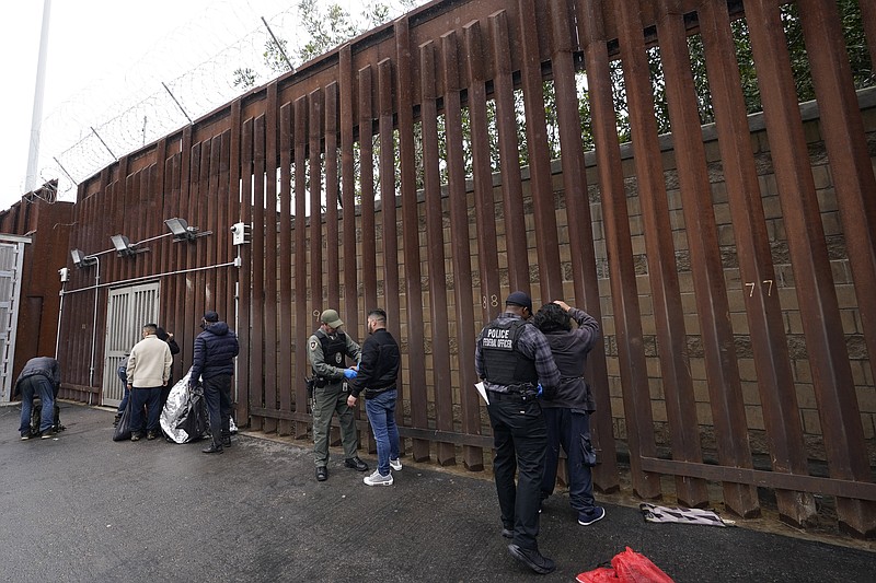 Oficiales federales estadounidenses le quitan las esposas a hombres antes de liberarlos cerca de la muralla fronteriza en San Diego el 15 de marzo de 2023. (Foto AP /Gregory Bull)