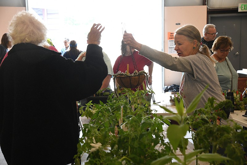 A vendor hands a plant to a customer Friday during the Garland County Master Gardeners' annual Plant Sale and Garden Show at the Garland County Fairgrounds. - Photo by Lance Brownfield of The Sentinel-Record