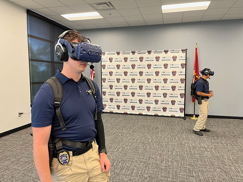 Officers Dillan Stephens (left) and Pietrie Yang (right) participate in a scenario-based training session on Friday, April 21, 2023, through the Apex Officer virtual reality training simulator at the Rogers Police Department. The department is the first law enforcement agency in Northwest Arkansas to adopt the Apex simulator. (Garrett Moore/NWA Democrat-Gazette)
