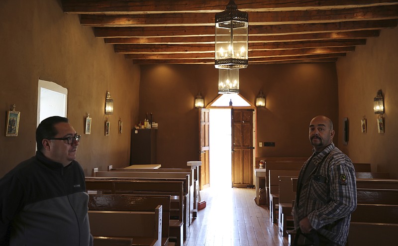 Fidel Trujillo, left, and Leo Paul Pacheco, stand inside the 1880s Santo Ni&#xf1;o de Atocha chapel in Monte Aplanado, New Mexico, on Saturday, April 15, 2023. Pacheco restored the adobe walls of the church, and hopes that his children will value doing the same in the future, maintaining cherished Catholic traditions in these remote mountain villages. (AP Photo/Giovanna Dell'Orto)