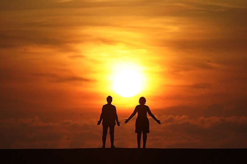 In this Sept. 19, 2020 file photo, a couple stands on a jetty as the sun rises over the Atlantic Ocean in Bal Harbour, Fla. For the millions of Americans who struggle with mental illnesses and wouldn't manage an inheritance wisely, trusts can be designed to ensure the money is used to their benefit. (AP file photo/Wilfredo Lee)