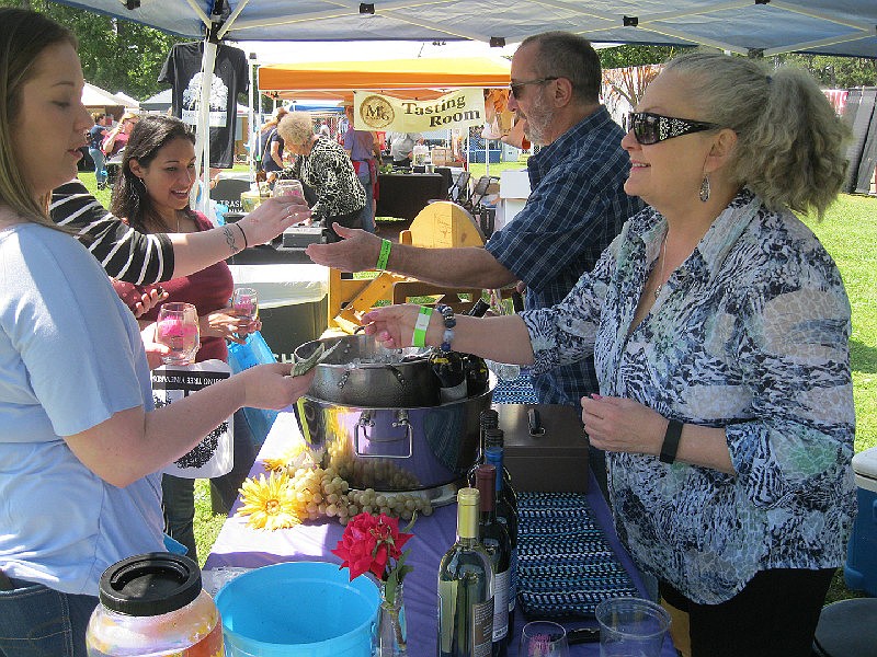 Paula Williamson and Mike Boase of Chisholm Trail Winery serve samples at the 2018 Twice as Fine Wine Festival in Spring Lake Park in Texarkana, Texas. (Gazette file photo)