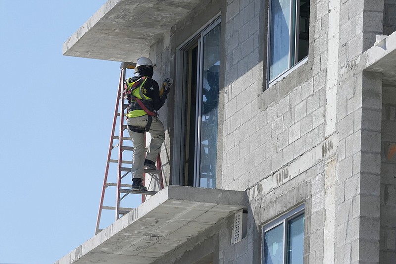 A construction worker sands a door opening at a new apartment complex, Tuesday, February 28, 2023, in Miami. (AP Photo/Marta Lavandier)