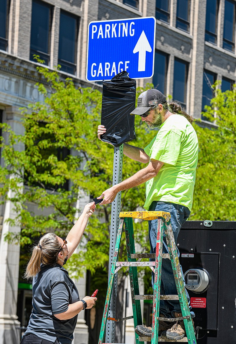 Julie Smith/News Tribune
Natasha Faulkner hands co-worker Tom Plugge pieces of tape so he can secure the black plastic over the parking limit sign in the 300 block of Madison Street Wednesday. Faulkner and Plugge work for Public Works Parking Division and charged with covering parking limit signs on the north and southbound streets while Streets Department staff covered the parking signs on the east and westbound streets. At Monday night's meeting, the City of Jefferson City Council voted to pause parking enforcement in un-metered spots in downtown. Right now it is for 30 days, but there is a possibility that it could be extended.