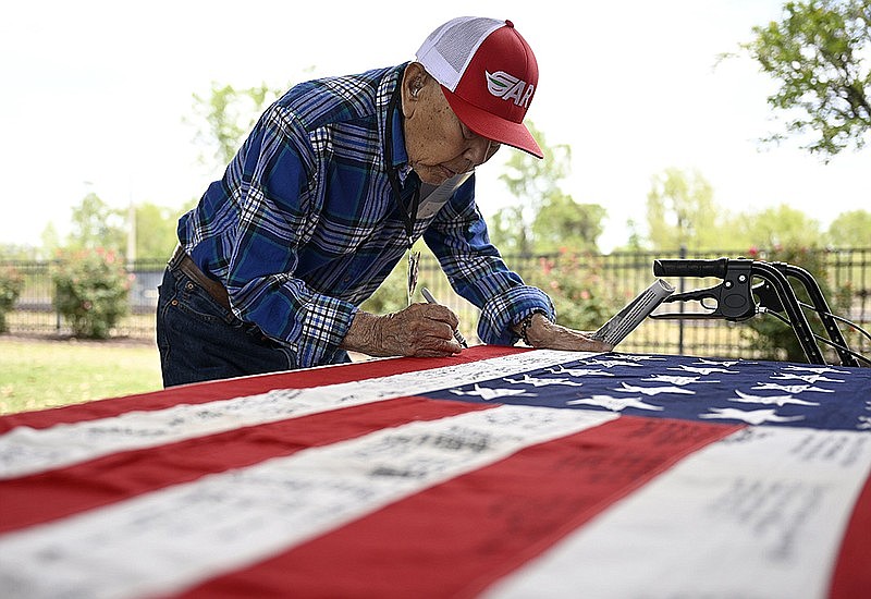 George Teraoka, who was interned at the Rohwer camp, writes his name on an American flag during a ceremony commemorating the 10th anniversary of the World War II Japanese American Internment Museum in McGehee on Thursday. Teraoka turns 102 on May 13. More photos at arkansasonline.com/55internment/. (Arkansas Democrat-Gazette/Stephen Swofford)