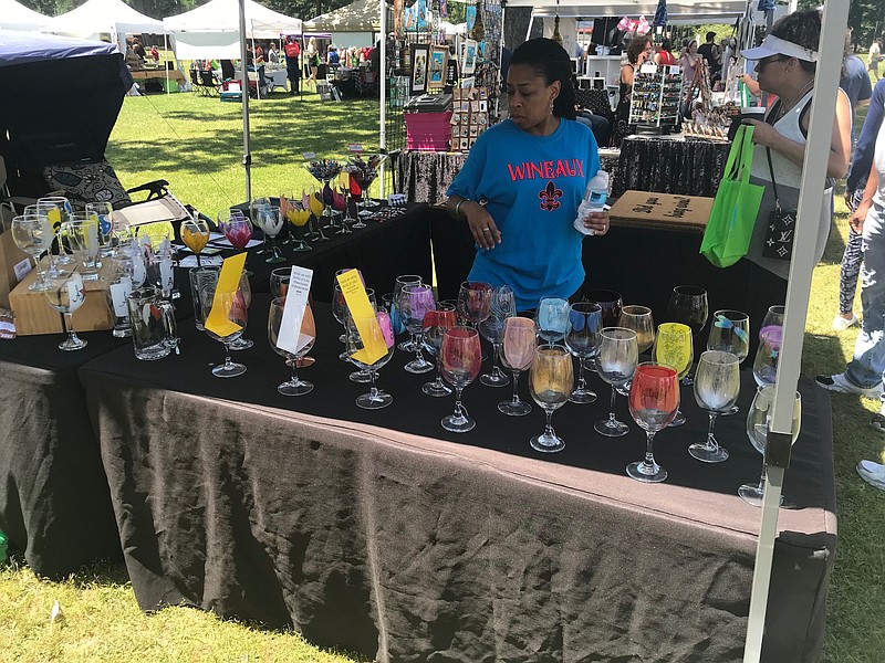 Billisha Hastings surveys her wine glass merchandise at the eighth annual Texarkana Wine Festival on Saturday, May 6, 2023, at Spring Lake Park. Hastings said she also paints wine glasses — a hobby she started about 12 years ago. (Staff photo by Greg Bischof)