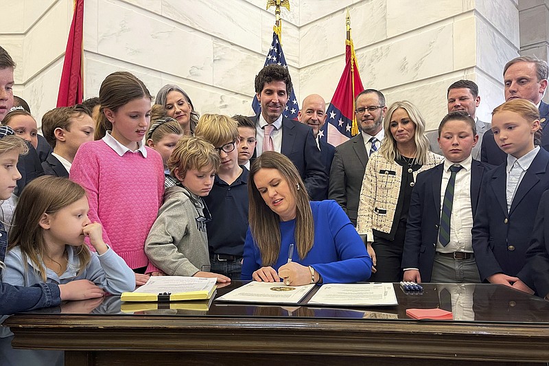 FILE - Arkansas Gov. Sarah Huckabee Sanders signs an education overhaul bill into law on March 8, 2023, at the state Capitol in Little Rock, Ark. A new lawsuit filed Monday, May 8, 2023, says the Arkansas Board of Education improperly voted to let a nonprofit charter schools organization manage a school district because a new law allowing such contracts has not yet taken effect. The suit challenges the Arkansas LEARNS Act that Sanders signed into law in March. (AP Photo/Andrew DeMillo, File)
