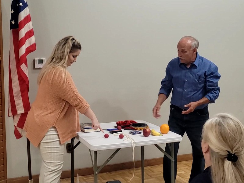 Photo By Bradly Gill
Lions Club Member Anna Norell assists Carley Davis with a magic trick during the Lions Club meeting. Davis says he uses his illusions to bring the message of Christ.