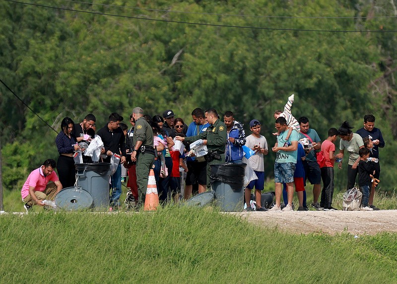 Immigrants walk to where the United States Border Patrol is processing them after they crossed into the U.S. from Mexico on Wednesday, May 10, 2023, in Brownsville, Texas. (Joe Raedle/Getty Images/TNS)