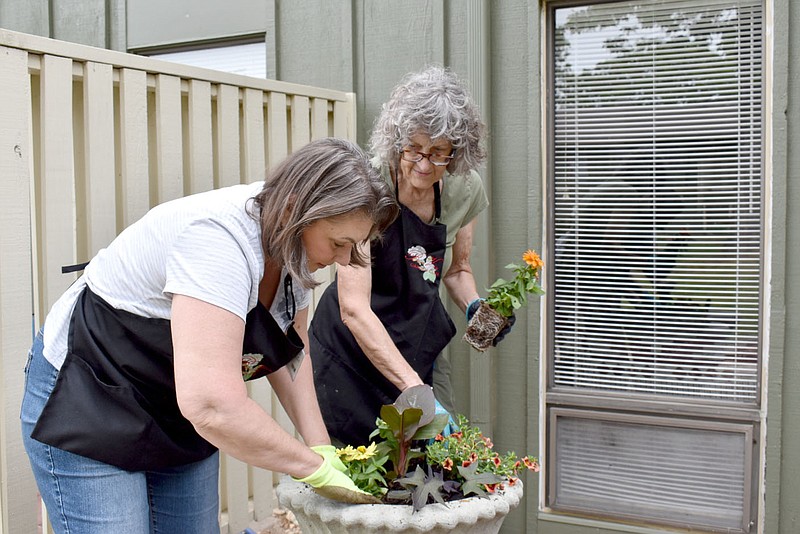 Rachel Dickerson/The Weekly Vista Bella Vista Garden Club members Louise Wilson, left, and Deidre Cheney fill a container garden for Molly Hardy outside her apartment at Concordia Retirement Community on May 10.