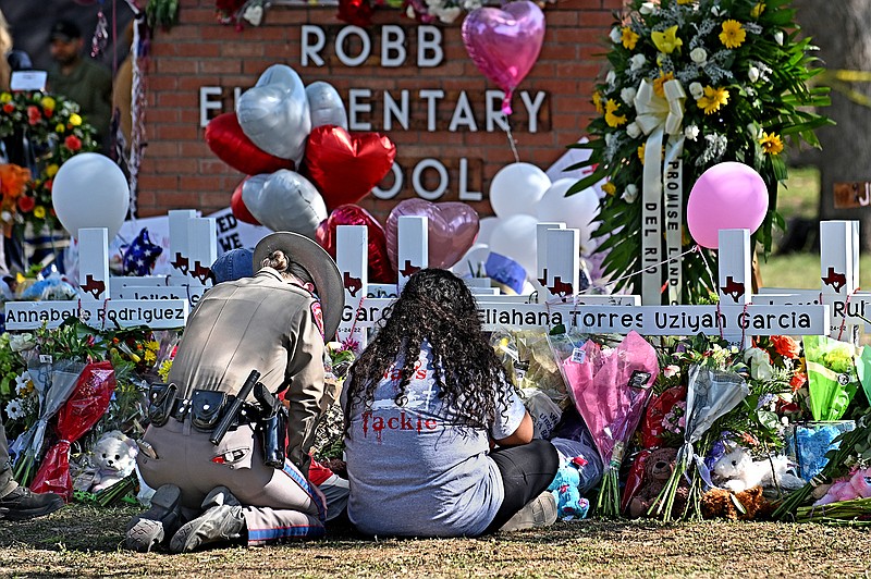 A police officer comforts family members at a memorial outside Rob Elementary School in Uvalde, Texas on May 26, 2022. Nineteen students and two teachers died when a gunman opened fire in a classroom Tuesday. (Wally Skalij/Los Angeles Times/TNS)