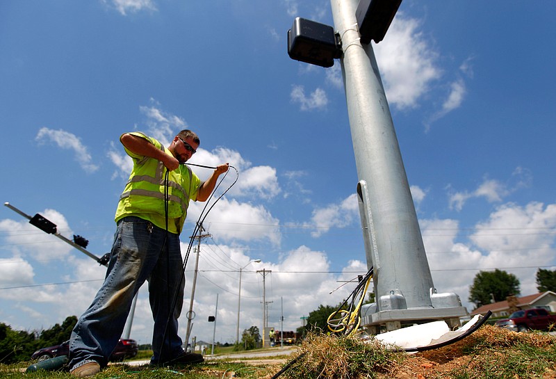 Shane Chamness and a crew with All Service Electric pull underground wires for traffic and crosswalk signals on Thursday, July 24, 2014, at the intersection of Don Tyson Parkway and 40th Street in Springdale. 
(NWA Democrat-Gazette)