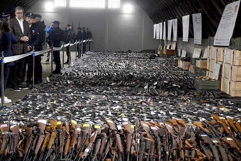 In this photo provided by the Serbian Presidential Press Service, Serbian President Aleksandar Vucic, left, inspects weapons collected as part of an amnesty near the city of Smederevo, Serbia, Sunday, May 14, 2023. Serbian authorities on Sunday displayed some of around 13,500 weapons they say have been collected since last week's mass shootings, including automatic weapons, hand bombs and anti-tank grenades. (Serbian Presidential Press Service via AP)