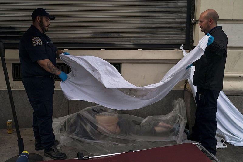 FILE - Forensic assistant Laurentiu Bigu, left, and investigator Ryan Parraz from the Los Angeles County coroner's office cover the body of a homeless man found dead on a sidewalk in Los Angeles on April 18, 2022. The 60-year-old man died from the effects of methamphetamine, according to his autopsy report. Drug overdose deaths in the U.S. went up slightly in 2022 after two big leaps during the pandemic. (AP Photo/Jae C. Hong, File)