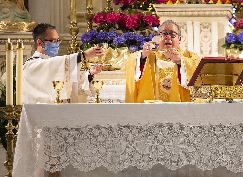 Bishop Michael Olson, right and deacon Linh Nguyen consecrate the host during mass at St. Patrick Cathedral on May 3, 2020, in Fort Worth. (Juan Figueroa/Dallas Morning News/TNS)