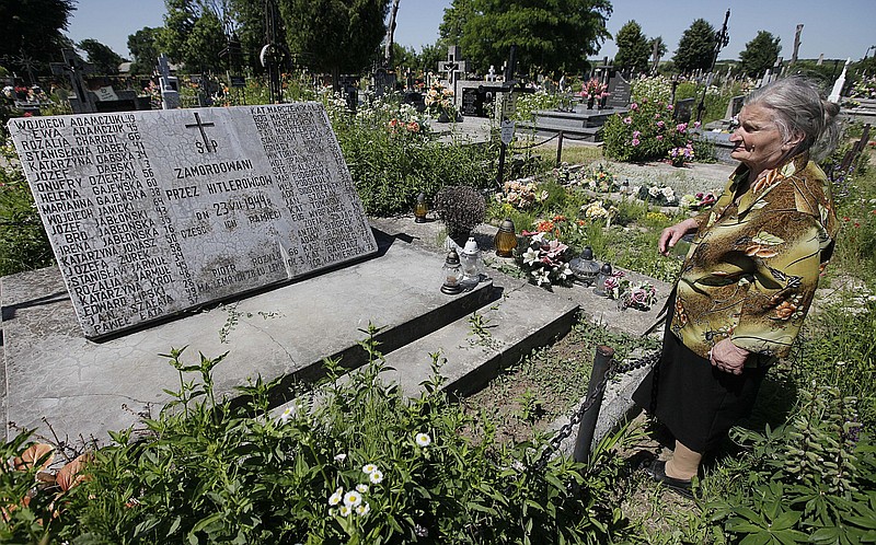 FILE - A woman stands near a mass grave and a monument in the village of Chlaniow, Poland, on June 19, 2013 that holds the bodies of Poles killed in a 1944 attack on the village by the Nazi SS-led Ukrainian Self Defense Legion. Officials in Poland and Ukraine, staunch strategic partners, have unexpectedly exchanged bitter remarks regarding a painful mutual past that includes mass murder. Seeking to calm emotions, an aide to Polands President Andrzej Duda said Monday May 22, 2023 that the Poles only wanted the truth and respect for the tens of thousands of Polish victims. (AP Photo/Czarek Sokolowski, File)