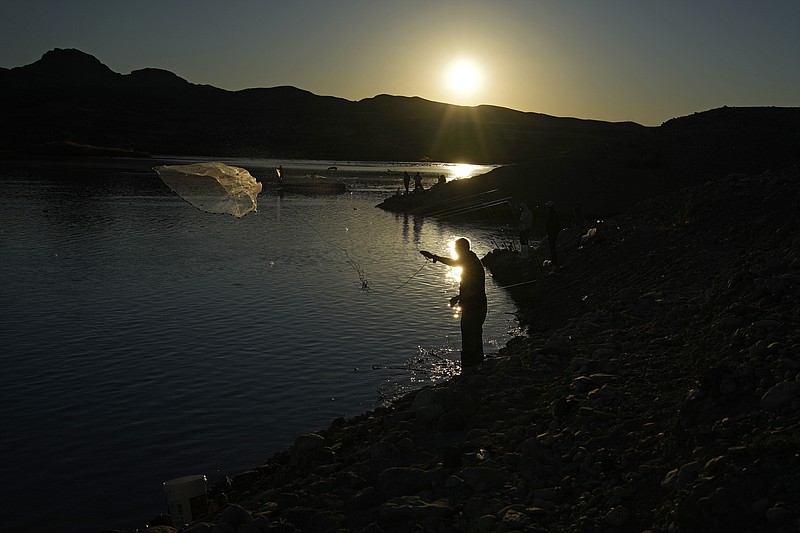 FILE - A fisherman throws a cast net along shore of Lake Mead at the Lake Mead National Recreation Area, Jan. 27, 2023, near Boulder City, Nev. Arizona, California and Nevada on Monday, May 22, proposed a deal to significantly cut their water use from the drought-stricken Colorado River over the next three years. (AP Photo/John Locher, File)