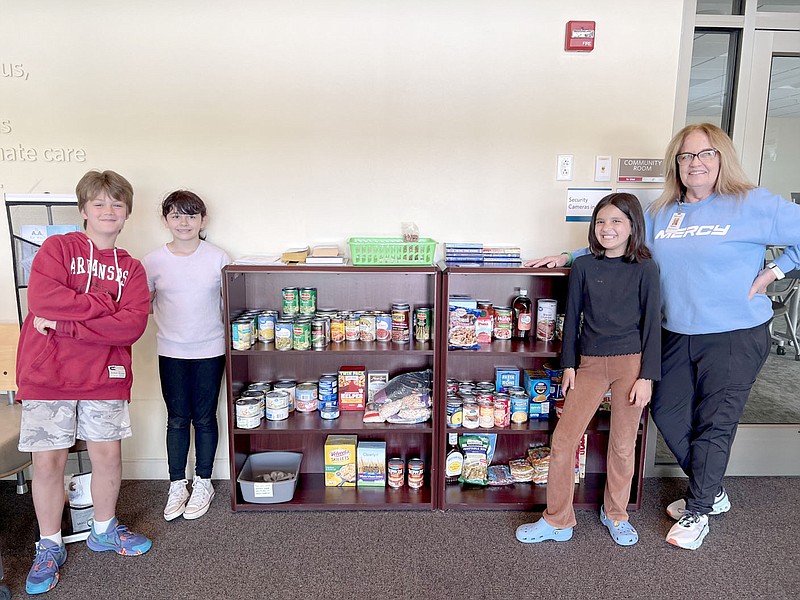 Submitted photo Cooper Elementary School Students (from left) Greyson Wegner, Ellie Dubon and Mariah Gonzale are pictured with Operations Supervisor Kimberly Franklin from Mercy-Bella Vista. The students in Leslie Andreasens fourth-grade class held a food drive to collect food for the pantry at Mercy and donated it as part of a class project.