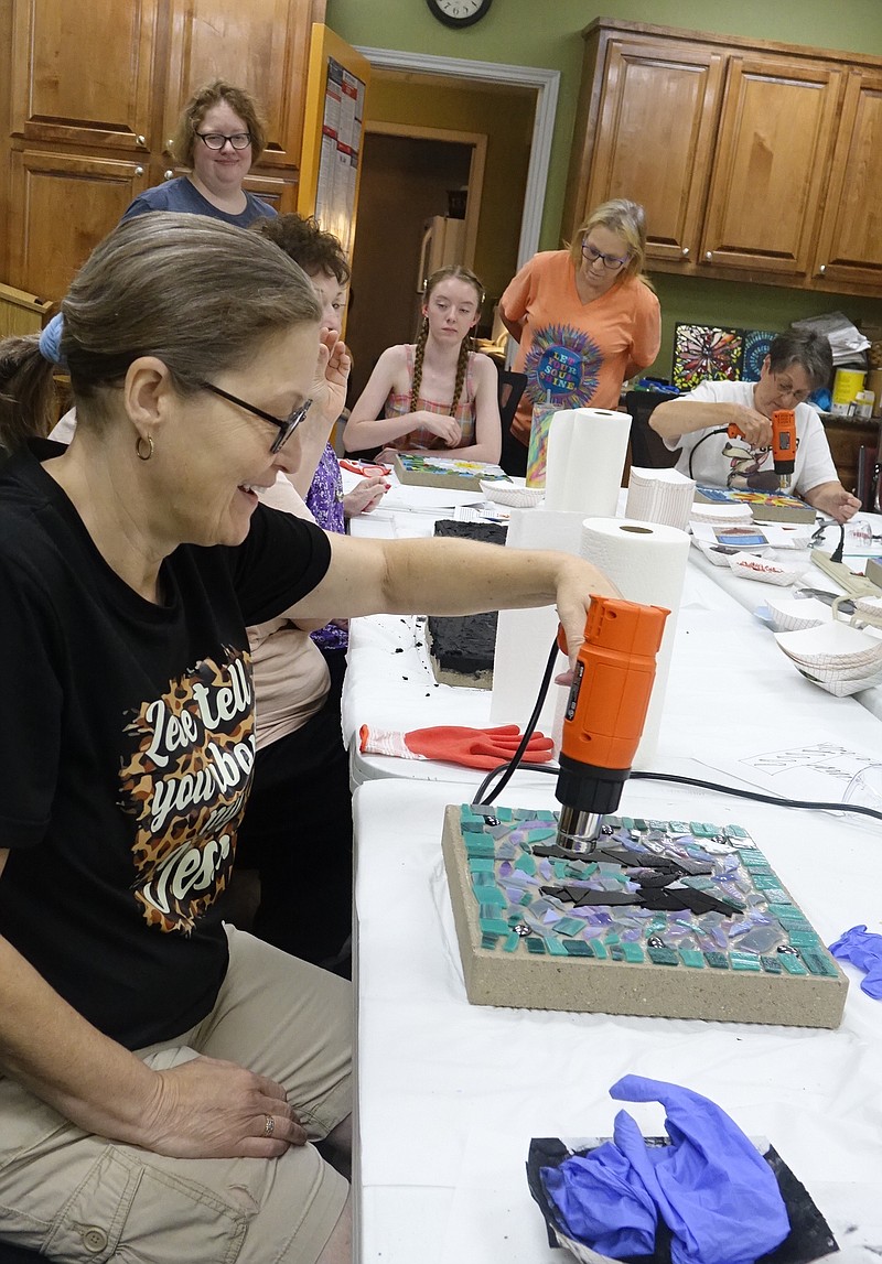 Lisa Brackman is applying heat to her stepping stone which will melt the glue holding the tesserae to a concrete block. Shes participating in the Atlanta Librarys recent mosaic stone craft class. Photo by Neil Abeles.
