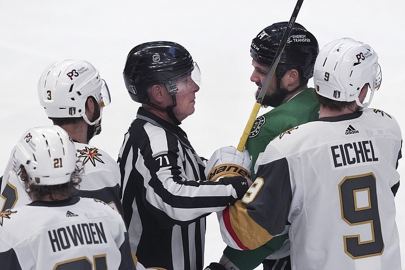 Dallas Stars left wing Jamie Benn (14) is held back by linesman Brad Kovachik (71) and Vegas Golden Knights center Jack Eichel (9) during the first period Tuesday in Dallas. - Photo by LM Otero of The Associated Press
