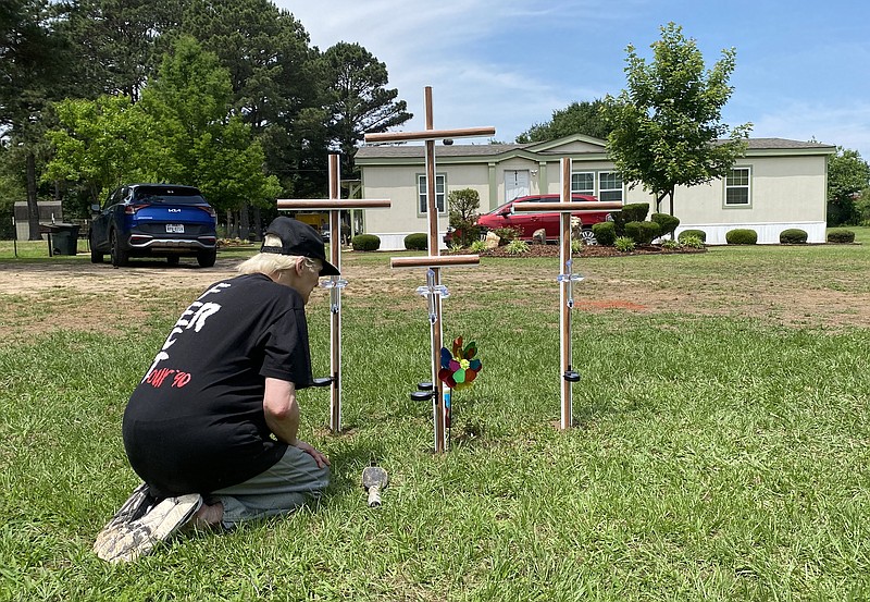 Charity Lopez installs four crosses in the front yard of the Olalde home Wednesday, May 24, 2023, on Lemon Acres in Nash, Texas. The crosses are a memorial to Reuben and Aida Olalde, daughter Lisbet and son Oliver. The four were killed Tuesday, May 23 in the home. Caesar Olalde, the Olaldes' 18-year-old son, has been charged with capital murder of multiple persons in the deaths. (Staff photo by Stevon Gamble)