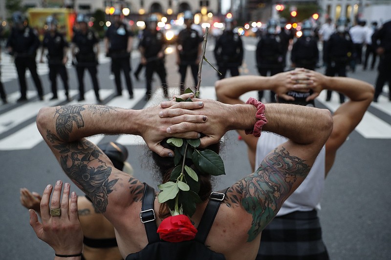 FILE - Protesters kneel in front of New York City Police Department officers before being arrested for violating curfew beside the iconic Plaza Hotel on 59th Street, June 3, 2020, in New York. Protests continued following the death of George Floyd, who died after being restrained by Minneapolis police officers on May 25. The third anniversary of Floyd&#x2019;s murder is Thursday, May 25, 2023. (AP Photo/John Minchillo, File)