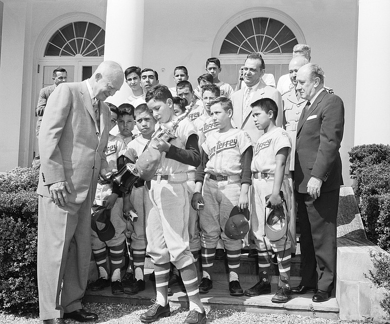 FILE - President Dwight D. Eisenhower looks at the Little League Championship Baseball trophy won by the Monterrey, Mexico, team on Aug 27, 1957, in Washington. The young ball players were accompanied to the White House by Mexican Ambassador Manuel Tello, right, and other embassy officials. Angel Macias holds the trophy. (AP Photo/Bill Allen, File)