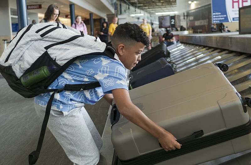 Lorenzo Smith, 11, of Dallas, Texas pulls a suitcase from a carousel, Thursday, May 25, 2023 at the Northwest Arkansas National Airport in Bentonville. Visit nwaonline.com/photos for today's photo gallery.

(NWA Democrat-Gazette/Charlie Kaijo)