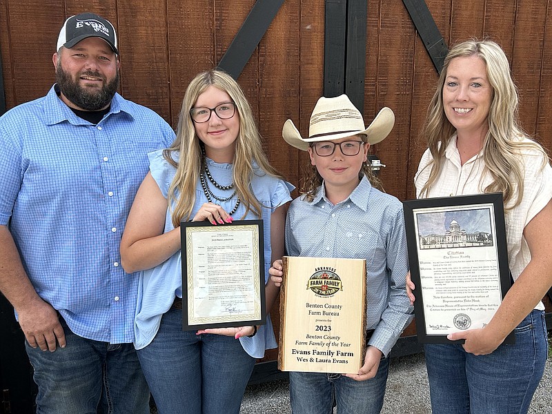 Wes Evans, daughter Emma, 14, son, Weston, 11, and wife Laura show the awards they received on Friday at Evans Cattle Company in rural Highfill during ceremonies honoring them as the 2023 Benton County farm family of the year. (NWA Democrat-Gazette/RANDY MOLL)