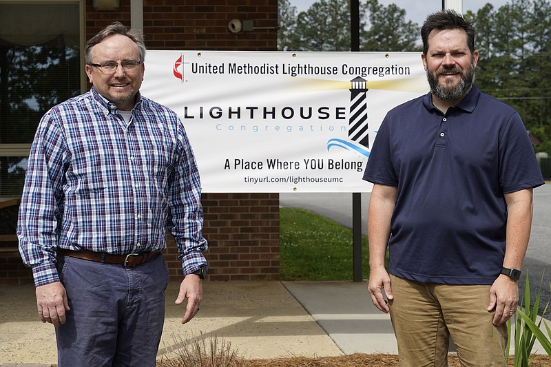 The Rev. Ed McKinney, pastor of Stokesdale United Methodist Church, left, and Michael Hahn, right, pose for a photo near a welcoming sign at the church May 15, 2023, in Stokesdale, N.C. Some United Methodist regional conferences have begun designating “Lighthouse” congregations — ones that actively welcome people who wanted to stay United Methodist but whose former churches voted to leave. Other conferences use different names, such as “Beacon” or “Oasis,” but the idea is the same. (AP Photo/Chuck Burton)