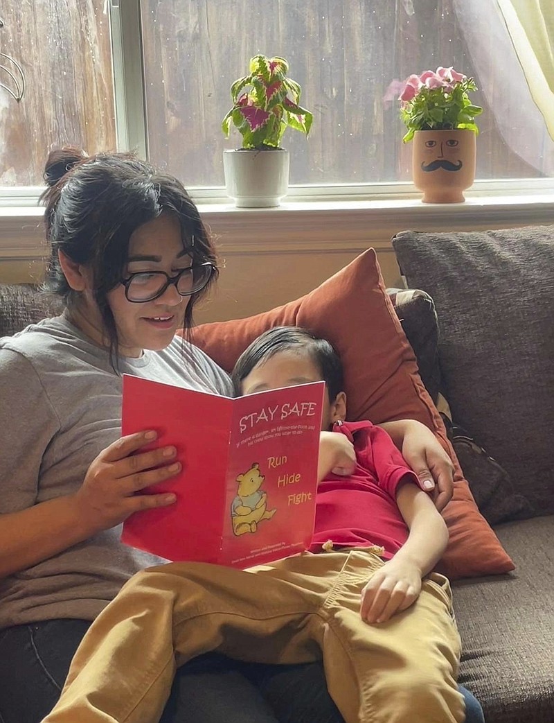 Cindy Campos reads the book "Stay Safe" to her son in Dallas. The 5-year-old was excited about the book that had been sent home with him from school featuring Winnie-the-Pooh that he wanted to read it immediately. But Campos' heart sank as she flipped through the pages advising children what to do if “danger is near,” including locking doors, turning off the lights and quietly hiding till police arrive. (Cindy Campos via AP)