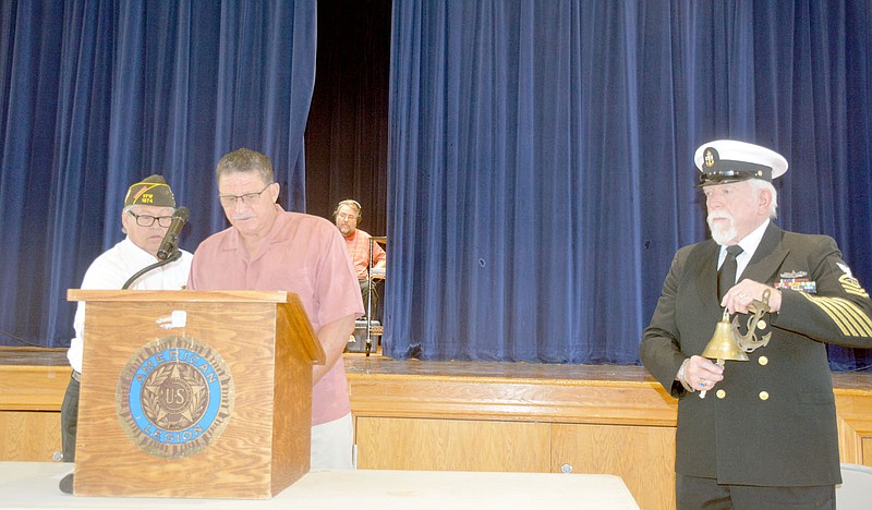 Marc Hayot/Herald-Leader VFW Post 1674 Commander Keith Schultz (left) and Charles Ricks read the names of service members who are on the KIA Memorial in Memorial Park as DAV Post 64 Commander Ron Evans sounds the bell after each name read. This ceremony was held during the American Legion Post 29's Memorial Day program on Monday at the Siloam Springs Community Building