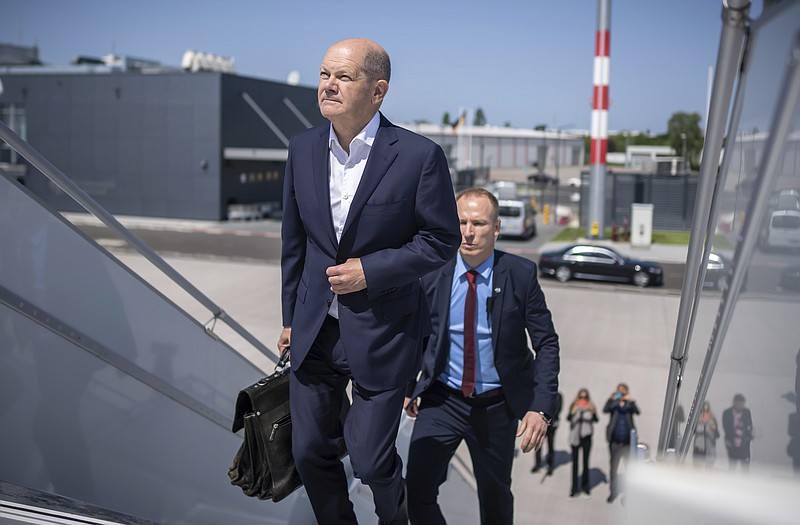 German Chancellor Olaf Scholz boards a government plane accompanied by bodyguards, officials of the Federal Criminal Police Office BKA, to travel to the meeting with the heads of government of the Baltic states in Tallinn, in Schonefeld, Germany, Friday May 26, 2023. (Michael Kappeler/dpa via AP)