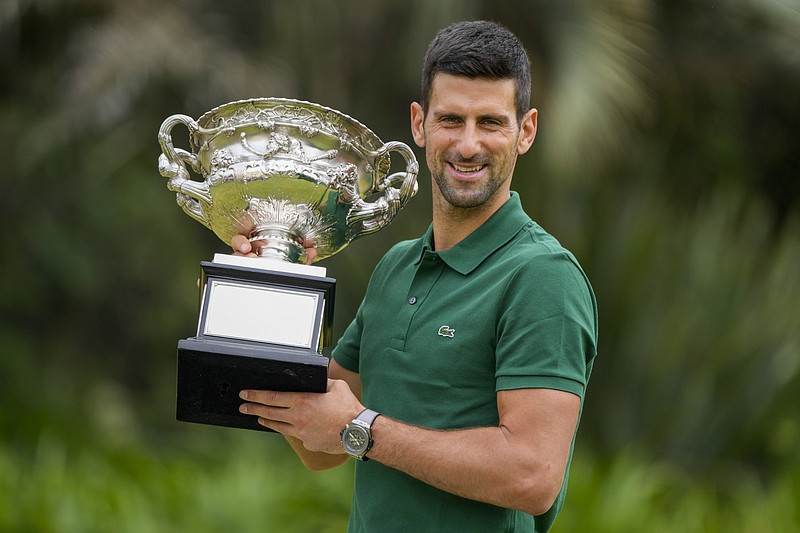 FILE -Novak Djokovic of Serbia poses with the Norman Brookes Challenge Cup in the gardens of Government House the morning after defeating Stefanos Tsitsipas of Greece in the men's singles final at the Australian Open tennis championship in Melbourne, Australia, Monday, Jan. 30, 2023. Novak Djokovic has made his long-term goal clear: He wanted to focus on accumulating Grand Slam titles in order to surpass the trophy total of rivals Rafael Nadal and Roger Federer. With the French Open set to start Sunday, May 28, 2023 without either the injured Nadal or the retired Federer, Djokovic gets the chance to finally lead the career standings alone with a mens-record 23 if he winds up with the championship two weeks from now.  (AP Photo/Mark Baker, File)