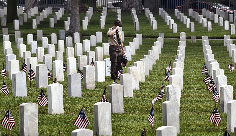 A Boy Scout salutes a fallen soldier after placing a flag at the foot of his gravesite at the Los Angeles National Cemetery on Saturday, May 27, 2023. The annual Memorial Day Flag Placement was held at Los Angeles National Cemetery where members of the Boy Scouts and other volunteers placed flags on the graves at the cemetery in West Los Angeles. (AP Photo/Richard Vogel)