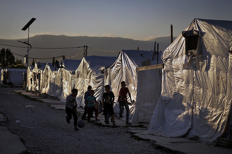 FILE - Syrian children play soccer by their tents at a refugee camp in the town of Bar Elias in the Bekaa Valley, Lebanon, July 7, 2022. The United Nations announced Saturday, May 27, 2023 that it will suspend a plan to begin making aid payments to Syrian refugees in crisis-wracked Lebanon in dollars, after pushback from local officials. (AP Photo/Bilal Hussein, File)