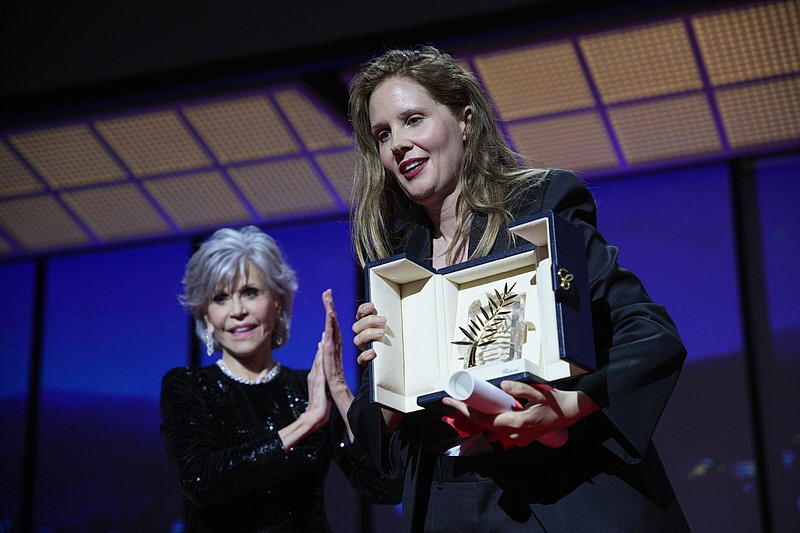 Justine Triet, right, accepts the Palme d'Or for 'Anatomy of a Fall,' which was presented by Jane Fonda, left, during the awards ceremony of the 76th international film festival, Cannes, southern France, Saturday, May 27, 2023 (AP Photo/Daniel Cole)