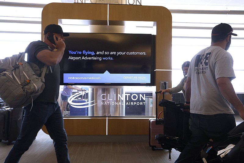 Travelers walk past an advertisement board in the baggage claim area of Bill and Hillary Clinton National Airport on Thursday, May 25, 2023, in Little Rock. 
(Arkansas Democrat-Gazette/Thomas Metthe)