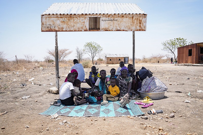 South Sudanese sit under the shade of a makeshift bus stop in Renk, South Sudan Wednesday, May 17, 2023. Tens of thousands of South Sudanese are flocking home from neighboring Sudan, which erupted in violence last month. (AP Photo/Sam Mednick)
