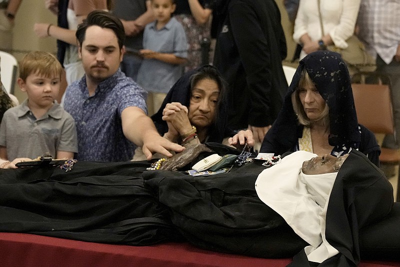 People pray over the body of Sister Wilhelmina Lancaster at the Benedictines of Mary, Queen of Apostles abbey Sunday, May 28, 2023, near Gower, Mo. Hundreds of people visited the small town in Missouri this week to see the nun's body that has barely decomposed since 2019 — some are saying it's a sign of holiness in Catholicism, while others are saying the lack of decomposition may not be as rare as people think. . (AP Photo/Charlie Riedel)