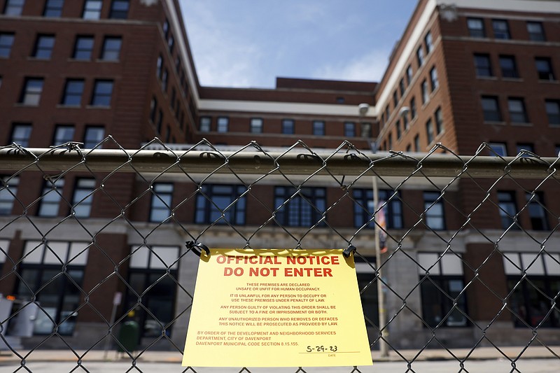 A yellow "official notice do not enter" sign hangs on a fence around The Davenport, 324 Main Street, after a partial building collapse, Monday, May 29, 2023, in Davenport, Iowa. A section of the six-story building downtown apartment building collapsed Sunday. City officials have announced the building will be demolished starting Tuesday. (Nikos Frazier/Quad City Times via AP)