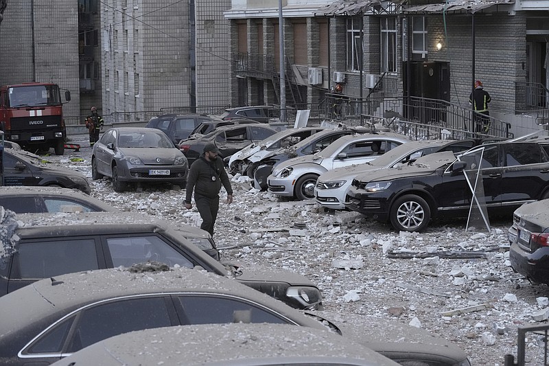 A police officer walks at the parking with damaged cars in front of a multi-story apartment building which was damaged during Russian attack in Kyiv, Ukraine, Tuesday, May 30, 2023. (AP Photo/Roman Hrytsyna)