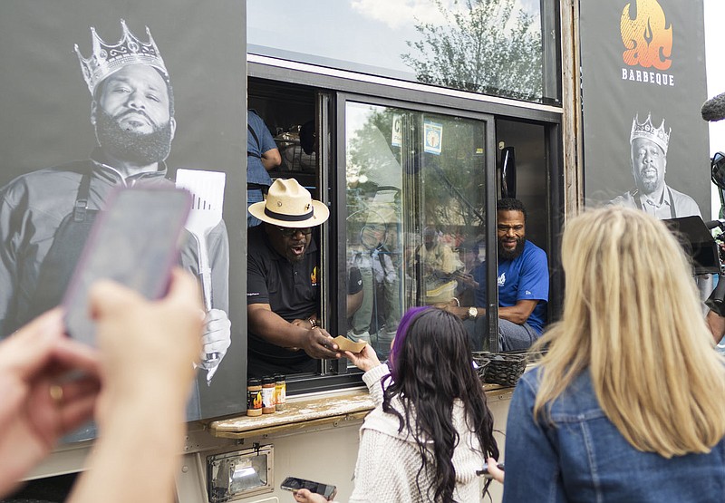 Cedric the Entertainer (from left) and Anthony Anderson serve barbecue to fans, Wednesday, May 31, 2023 along Emma Ave. in Downtown Springdale. Actor and comedian duo Anthony Anderson and Cedric the Entertainer visited Springdale for a community barbecue that is part of filming for their new show Kings of BBQ on A+E. They partnered with Yeyos owner Rafael Rios to provide food for a line of hungry fans along with Springdale Mayor Doug Sprouse and his wife. Visit nwaonline.com/photos for today's photo gallery.

(NWA Democrat-Gazette/Charlie Kaijo)