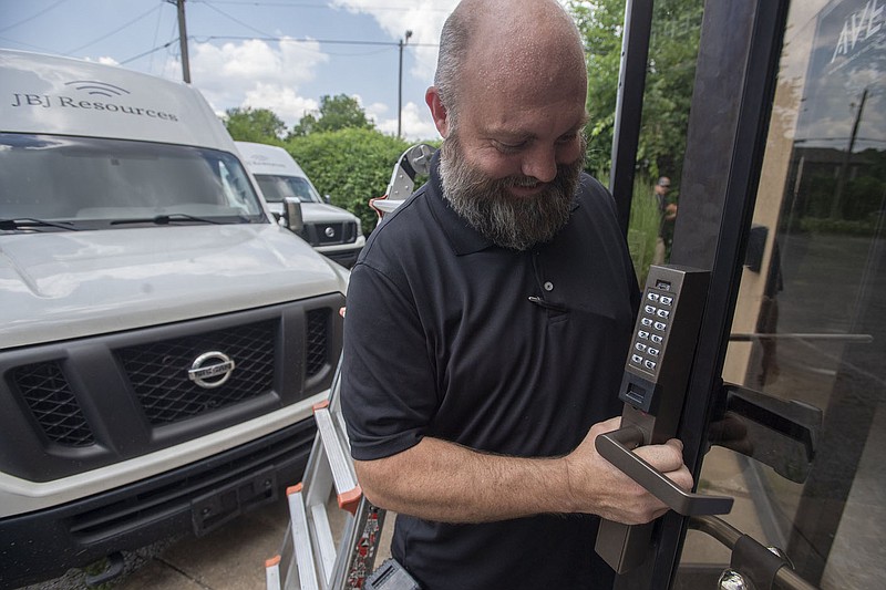 Joshua Jones, owner of Sharpâ€™s Lock & Alarm, installs a stand-alone storefront access control system Friday June 2, 2023 at a Fayetteville business. Fayetteville is considering changes to its ordinance dealing with false security alarms, including reducing the fees property and business owners can get for having too many in a year.  Visit nwaonline.com/photo for today's photo gallery.   (NWA Democrat-Gazette/J.T. Wampler)