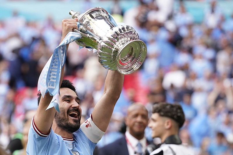Manchester City's Ilkay Gundogan holds up the winners trophy as he celebrates winning the English FA Cup final soccer match between Manchester City and Manchester United at Wembley Stadium in London, Saturday, June 3, 2023. Manchester City won 2-1. (AP Photo/Dave Thompson)