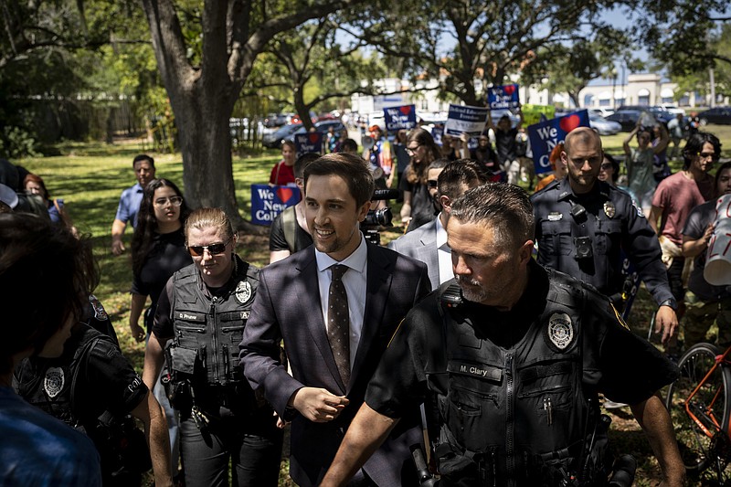 Christopher Rufo, a conservative activist and New College of Florida trustee, walks through protesters on his way out of a bill-signing event featuring Florida Gov. Ron DeSantis in Sarasota, Fla., on May 15. MUST CREDIT: Photo for The Washington Post by Thomas Simonetti