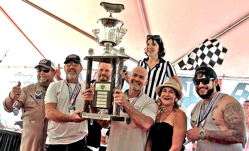 Bath Bombs Away, an entry in the Traditional Cast Iron Tubs division by Twisted Fork of Texarkana, Texas, won the coveted Traditional World Champion trophy during the running of the Stueart Pennington World Championship Running of the Tubs on Saturday, June 3, 2023, in downtown Hot Springs. VHS Special Events Manager Alexis Hampo, striped shirt, announced the win. (Photo by Lance Porter of The Sentinel-Record)