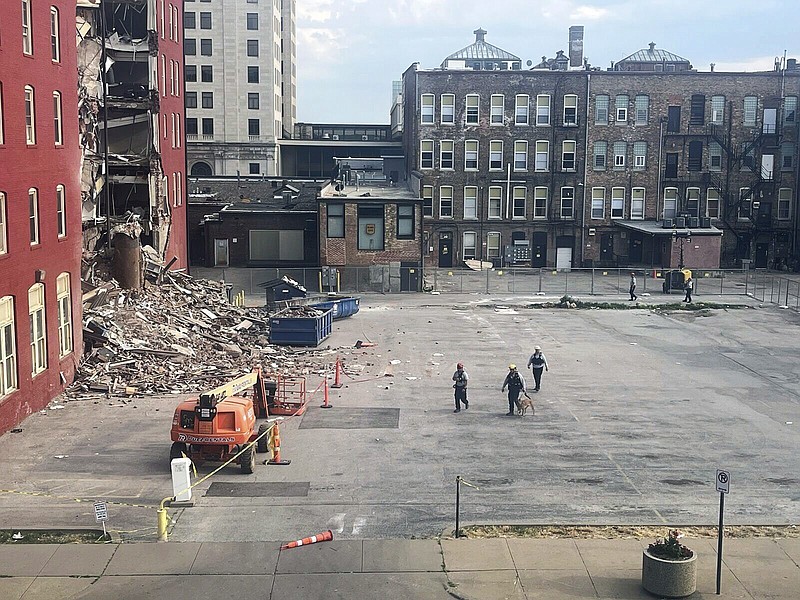 Three search and rescue workers and a dog approach the site of a building collapse in Davenport, Iowa, during a search, Thursday, June 1, 2023. (Grace Kinnicutt/Quad City Times via AP)