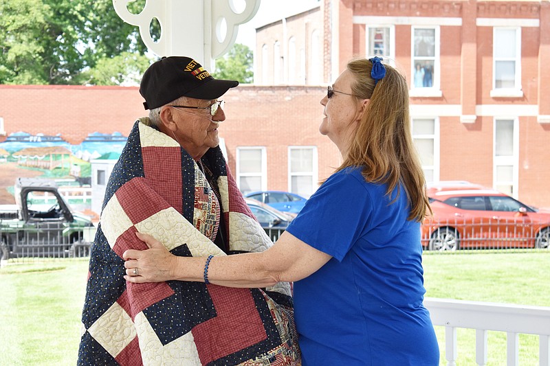Democrat photo/Garrett Fuller — Connie Richards, right, of Mid-Missouri Quilts of Valor, thanks Richard Ott for his military service after wrapping him Friday in his personalized quilt at the Latham Memorial Family Park in California. Ott served three tours in Vietnam between 1965-68 while serving aboard the USS Estes.